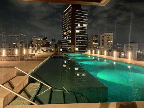 a large swimming pool with a city skyline at night at Bexp Spaces | VN Capote Valente in São Paulo