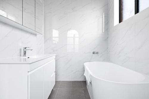 a white bathroom with a tub and a sink at Cozy Bankstown Stayz in Bankstown