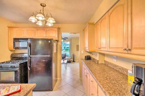 a kitchen with wooden cabinets and a stainless steel refrigerator at Palm Wave Says - Cozy - 2 Jacuzzis - Quiet Street in West Palm Beach