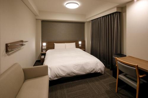 豊橋市にあるドーミーインEXPRESS豊橋のベッドとデスクが備わるホテルルームです。