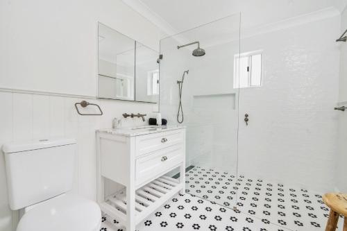 ein weißes Bad mit einem Waschbecken und einer Dusche in der Unterkunft Cherry Tree Cottage, Burrawang, Southern Highlands in Burrawang