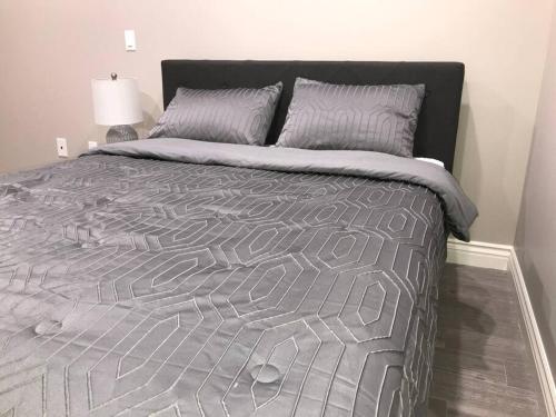a bed with a gray comforter and two pillows at New! Modern Gated Summer Getaway Home in Rosemead