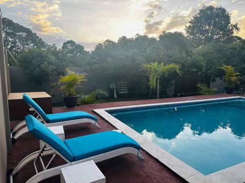 una piscina con 2 sillas azules al lado en Payes Home en Siguatepeque