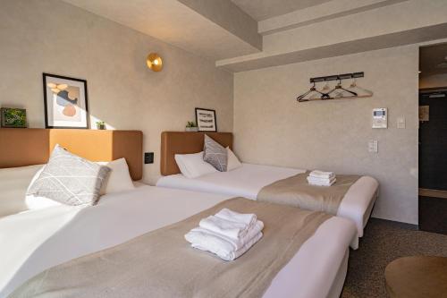 - 2 lits dans une chambre d'hôtel avec des serviettes blanches dans l'établissement Apartment Hotel 11 Kuromon II, à Osaka