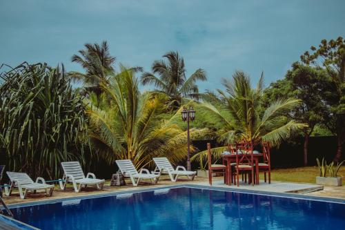 een tafel en stoelen naast een zwembad bij Aqua Hotel Yala in Yala