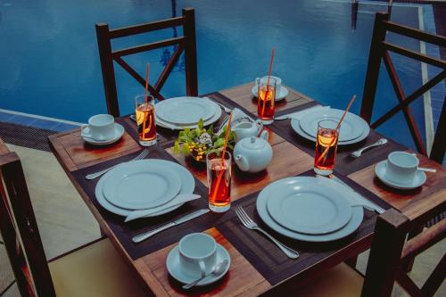 una mesa de madera con platos y utensilios. en Aqua Hotel Yala, en Yala