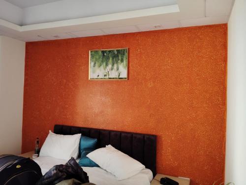 1 dormitorio con pared de color naranja y 1 cama con almohadas en Spark inn, en Gurgaon