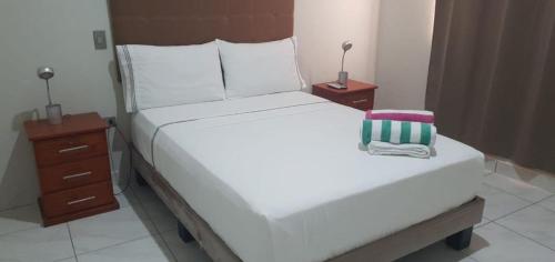 a bedroom with a large white bed and two night stands at HospedajesPerú in Zorritos