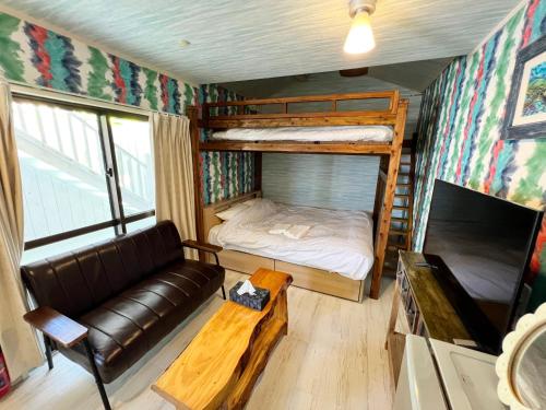 ein Wohnzimmer mit einem Sofa und einem Etagenbett in der Unterkunft Shiawaseninaru Kourijima no Yado in Nakijin