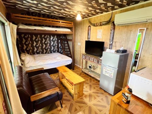 a room with a bed and a tv and a couch at Shiawaseninaru Kourijima no Yado in Nakijin