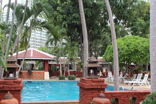 a swimming pool with a gazebo and palm trees at Safari Riviera Resort in North Pattaya