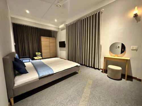 1 dormitorio con cama, escritorio y cortinas en Quê Mình - Hotel & Coffee, 