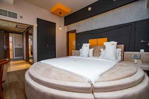 Un dormitorio con una cama grande con una gran colcha blanca en Gold Crest Hotel en Mwanza