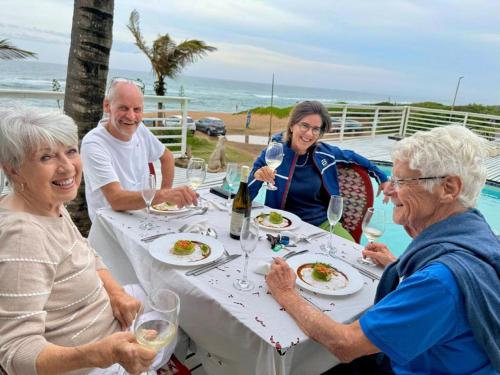 a group of people sitting at a table eating food at Bentley on the Beach in Umhlanga