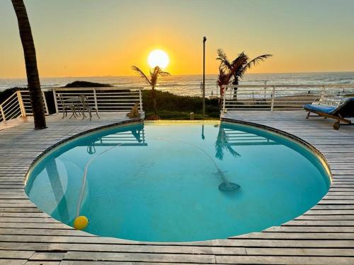 a swimming pool with a sunset in the background at Bentley on the Beach in Durban