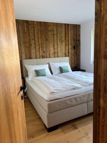 een slaapkamer met een bed met een houten muur bij GreenView Appartement in Wiesing