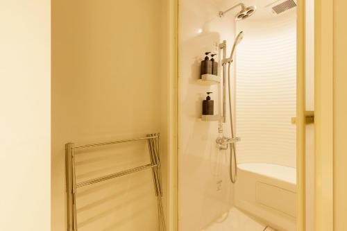 uma casa de banho branca com um chuveiro e um lavatório. em Hotel Re:ONcE Shibuya em Tóquio