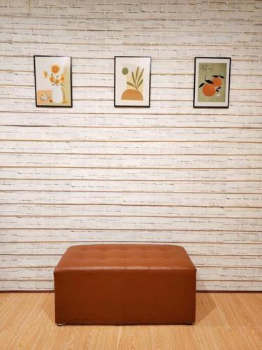 a brown ottoman in front of a wall with three pictures at 207:Homely room in apartment Near BTS Kasetsart U. in Bangkok