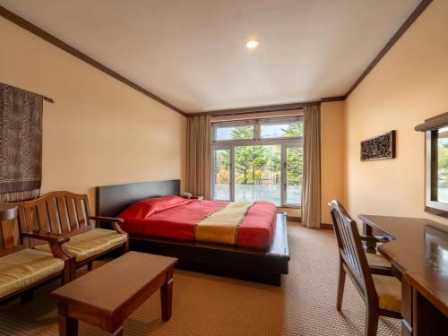 a bedroom with a bed and a chair and a window at Wellness Forest Nasu in Nasu