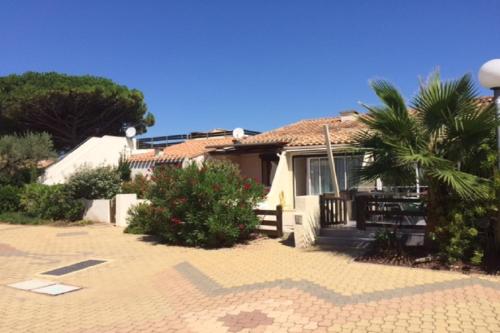 una casa con una palmera delante de ella en Cap d' Agde Naturist Hélio-village villa 58, en Cap d'Agde