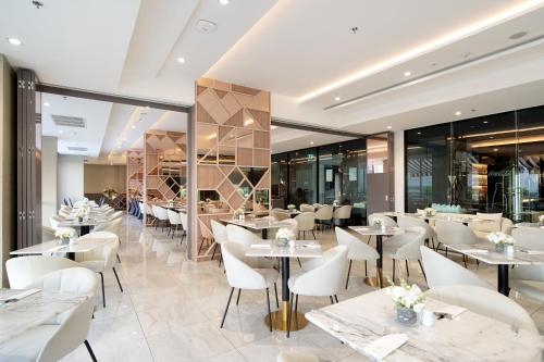 a restaurant with white tables and chairs and windows at Thaya Hotel Bangkok in Bangkok