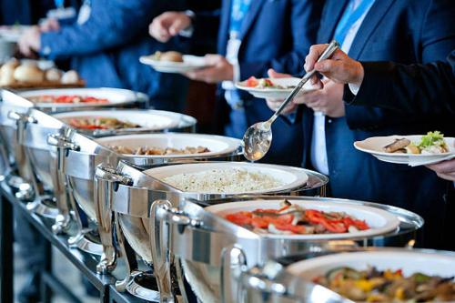 un grupo de personas sosteniendo platos de comida en Hotel Sundram, en Zirakpur