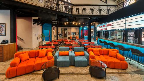 a bar with orange chairs and tables in a restaurant at Prince Theatre Heritage Stay Hostel - Silom in Bangkok