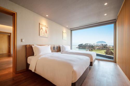 - 2 lits dans une chambre d'hôtel avec une grande fenêtre dans l'établissement Ananti at Namhae, à Namhae