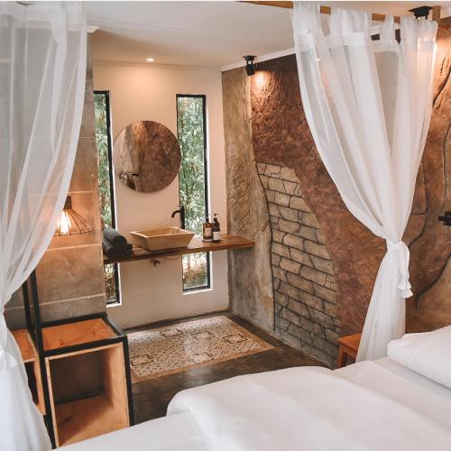 sypialnia z 2 łóżkami i kamienną ścianą w obiekcie Umbral Hotel Boutique w mieście Villavicencio
