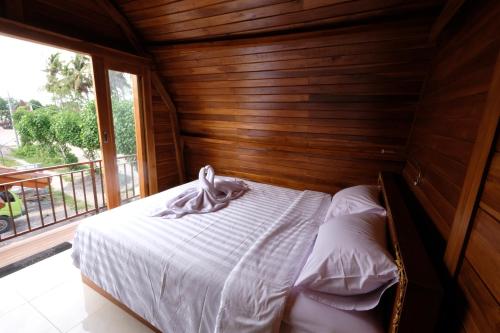 a bed in a wooden room with a window at Garuda Hostel & Accomodation Nusa Penida in Nusa Penida