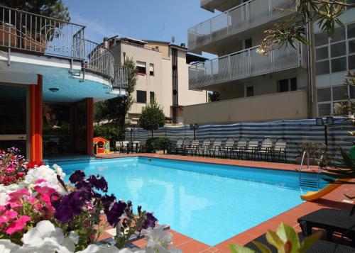 a swimming pool with flowers in front of a building at Hotel Universo in Rimini