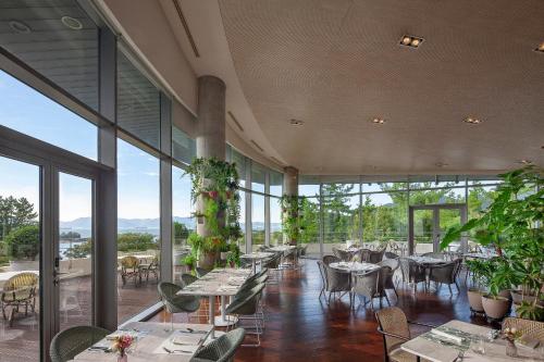 a restaurant with tables and chairs and large windows at Ananti at Namhae in Namhae