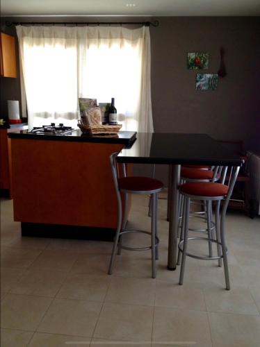 a kitchen with a table and two bar stools at Mi Valle Rural in Casas del Castañar