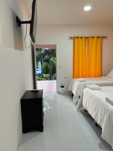 a bedroom with two beds and an orange curtain at Hotel Campestre Bella Vista Ometepe in Moyogalpa