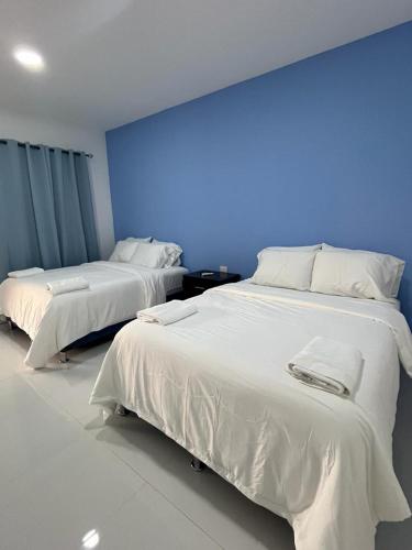two beds in a room with a blue wall at Hotel Campestre Bella Vista Ometepe in Moyogalpa
