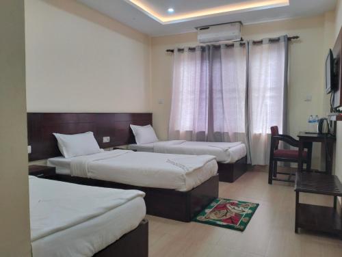 a hotel room with two beds and a desk at HOTEL OCEAN in Lumbini