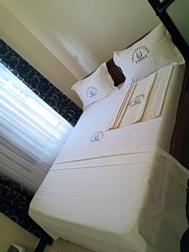 Cama blanca en habitación con ventana en G & S Executive Lodge, en Dar es Salaam