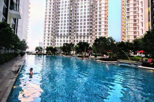 un garçon nageant dans une grande piscine d'une ville dans l'établissement Comfort 2 Bedroom Duplex @ Cyberjaya Netflix, à Cyberjaya