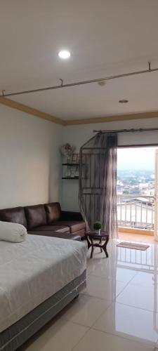 een slaapkamer met een bed, een bank en een raam bij APARTMEN MTC MEGAMAS in Manado