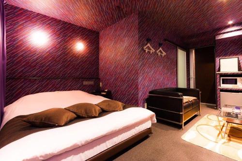 a bedroom with a purple wall with a bed and a chair at ホテルR -Adult only- in Gotemba