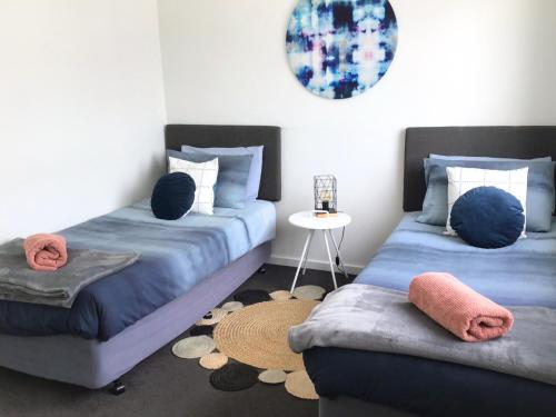 1 dormitorio con 2 camas y mesa en Discover Warilla - Bright and Airy Townhouse near the Beach and Lake, en Lake Illawarra