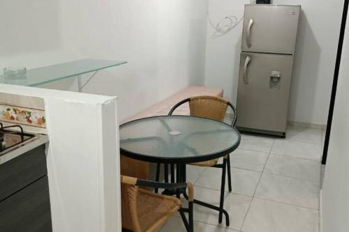 een keuken met een glazen tafel en een koelkast bij Aparta estudio Puerta del Norte Niquia in Bello