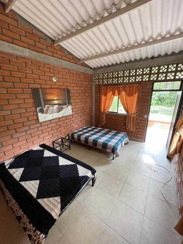 een kamer met 2 bedden en een bakstenen muur bij Condominio la laguna in La Rochela