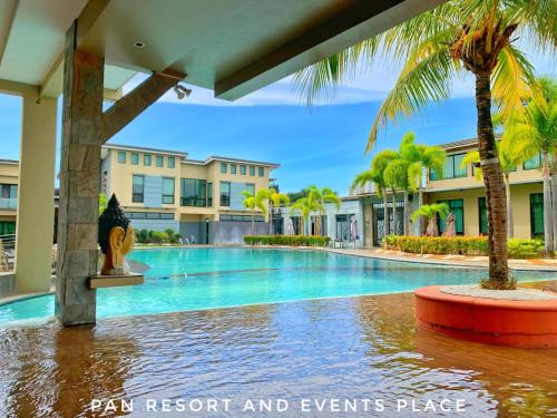 a swimming pool with palm trees and buildings at PAN HOTEL AND RESORT in Abucay