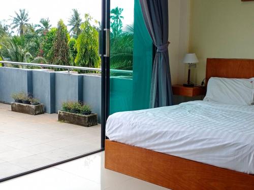 a bedroom with a bed and a view of a balcony at Sj House Hotel Aonang in Ban Khlong Haeng