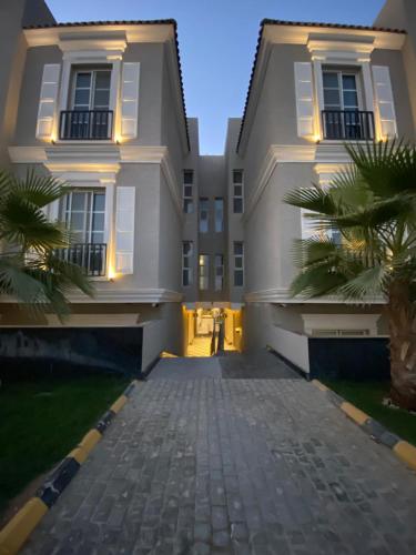 a large white building with palm trees in front of it at Elegant 3BD Condo near Boulevard in Riyadh