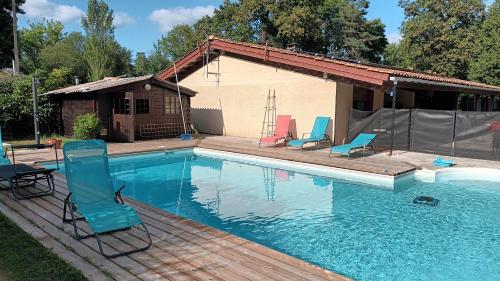 a swimming pool with chairs and a house at La chambre du Gaille in Captieux