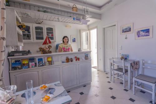 a woman standing behind a counter in a kitchen at Sofi pension in Naxos Chora