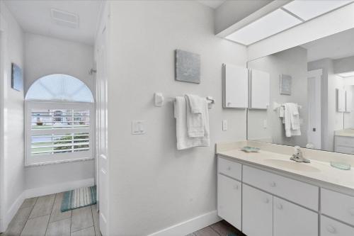 La salle de bains blanche est pourvue d'un lavabo et d'un miroir. dans l'établissement 3 BR Private Vacation Home, à Punta Gorda