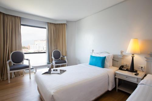 チェンマイにあるCH Hotelの大きなベッドと窓のあるホテルの部屋
